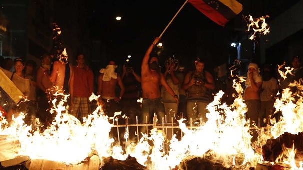 Anti-government demonstrators put up barricades and set fire...
